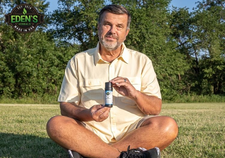 elderly man in park using eden's herbals cbd salve stick for joint pain
